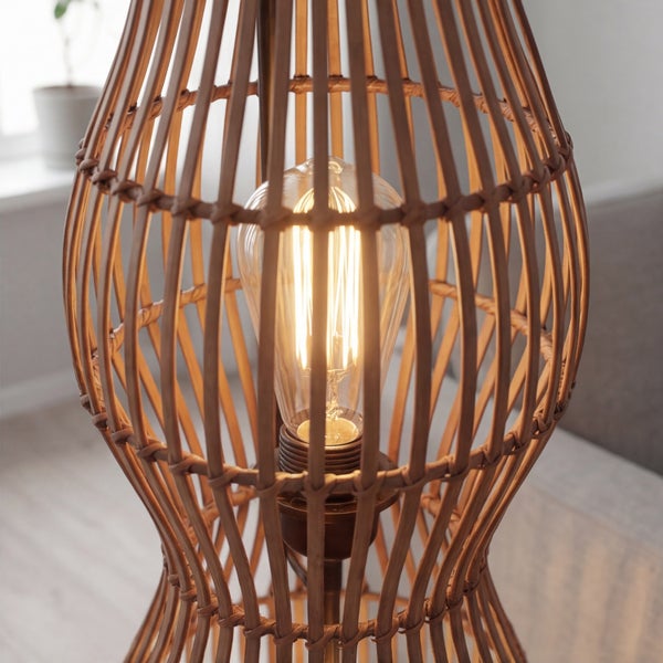 Detailaufnahme einer Leuchte aus Rattan-Geflecht mit einem eingeschalteten Leuchtmittel im Vintage-Stil.
