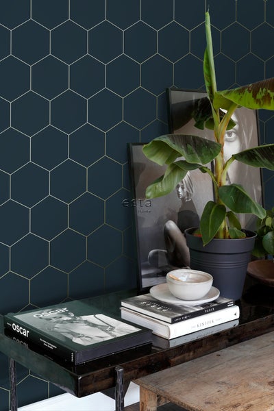 Dekoratives Interieur mit Wandtapete im geometrischen Hexagon Design, Pflanze und Dekoobjekten auf einem Tisch