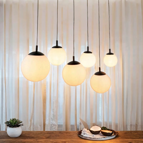 Mehrflammige Pendelleuchte mit runden Lampenschirmen über einem Holztisch