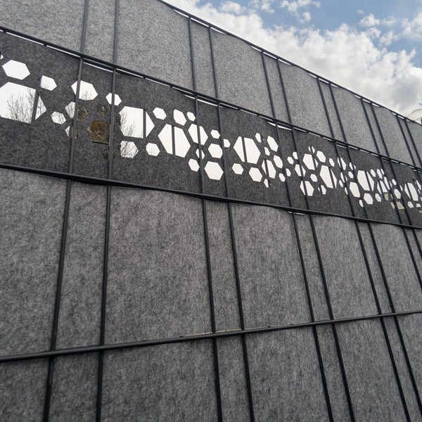 Graue Sichtschutzwand mit dekorativen Aussparungen im geometrischen Muster.