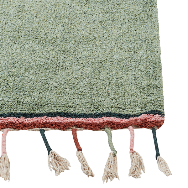 Salbeigrüner Hochflor-Teppich mit farbigem Rand und dekorativen Quasten.