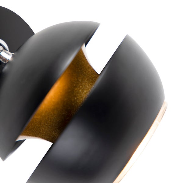 Detailaufnahme eines Wandstrahlers aus Metall, schwarzer Schirm mit goldfarbener Innenseite.