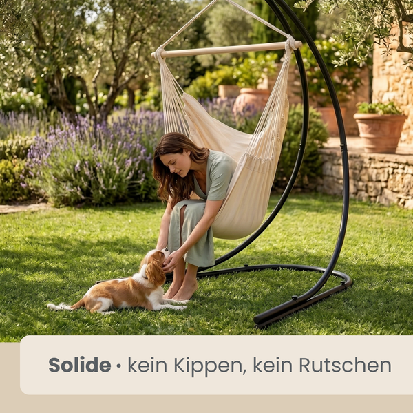 Frau im beigen Hängesessel mit Holzstab und stabilem Metallgestell im sonnigen Garten, streichelt einen Hund auf dem Rasen neben Lavendel.
