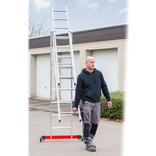 Handwerker transportiert eine ausziehbare Aluminium Mehrzweckleiter mit Rollbalken auf einem asphaltierten Platz.