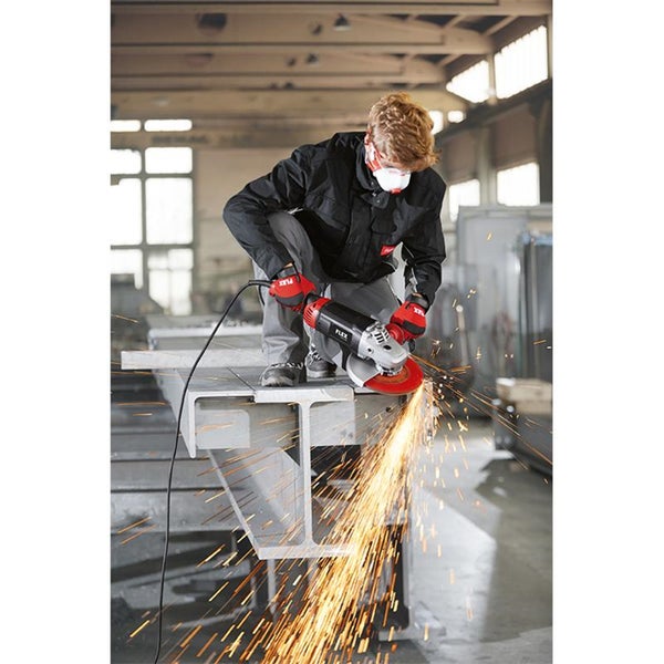 Handwerker mit Schutzkleidung und Atemschutz beim Trennen eines Stahlträgers mit einem Winkelschleifer in einer Werkstatt