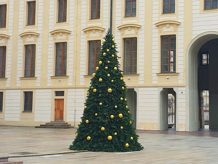 Ein grosser geschmückter Weihnachtsbaum mit goldenen Kugeln vor einer historischen Schlossfassade.