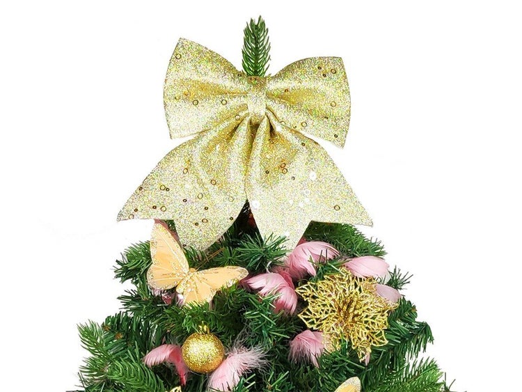 Weihnachtsbaumspitze in Form einer glitzernden Schleife auf einem künstlichen Weihnachtsbaum dekoriert mit Federn und weihnachtlichen Ornamenten.