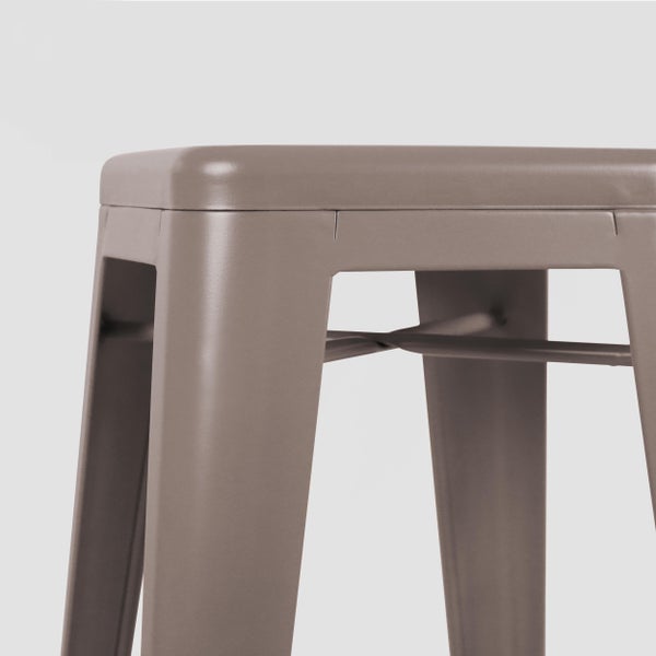 Detailansicht eines taupefarbenen Metallhockers mit quadratischer Sitzfläche und stabilisierenden Querstreben.