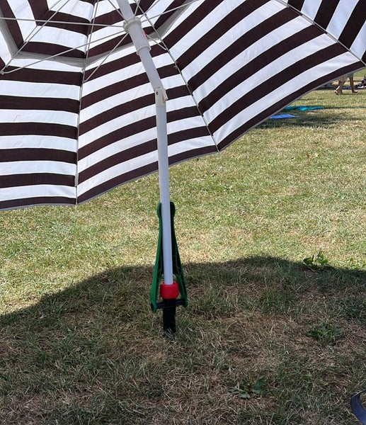 Bodenhülse für Sonnenschirme aus Kunststoff im Einsatz auf einer Rasenfläche mit einem gestreiften Sonnenschirm.