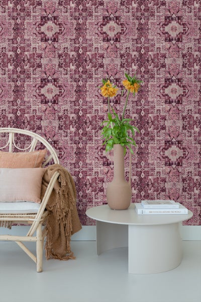 Dekoratives Zimmer mit gemusterter Tapete, Sessel, Tisch und Blumenvase