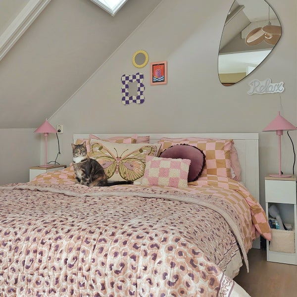 Schlafzimmer mit Bett, Nachttischen, Lampen, Dekorationen und einer Katze