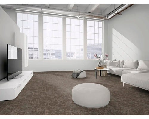 Dunkler Teppichboden mit Kreuzschraffur in einem hellen, modernen Wohnzimmer mit großen Fenstern, weißem Sofa und industriellen Details.