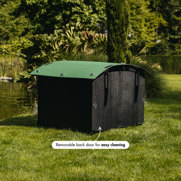 Entenhaus auf Rasen am Wasser mit einer Frau und Enten, geeignet für bis zu acht kleine Enten oder zwei große Gänse.