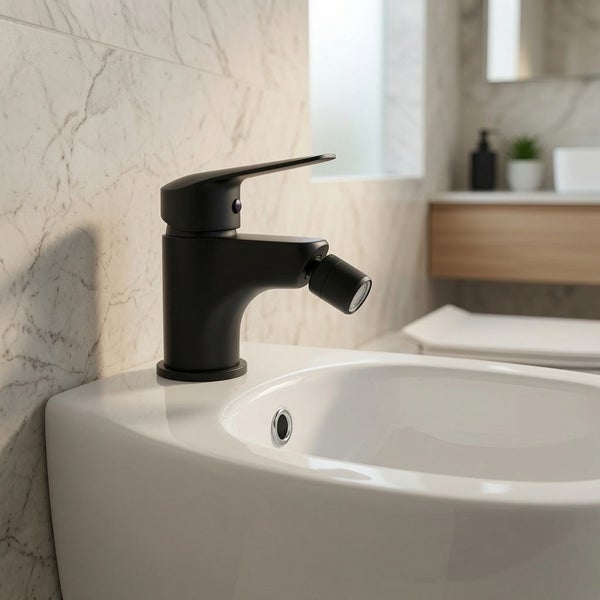 Schwarze Einhebel-Bidetarmatur auf weißem Bidet in hellem Badezimmer mit Wandfliesen in Marmoroptik.
