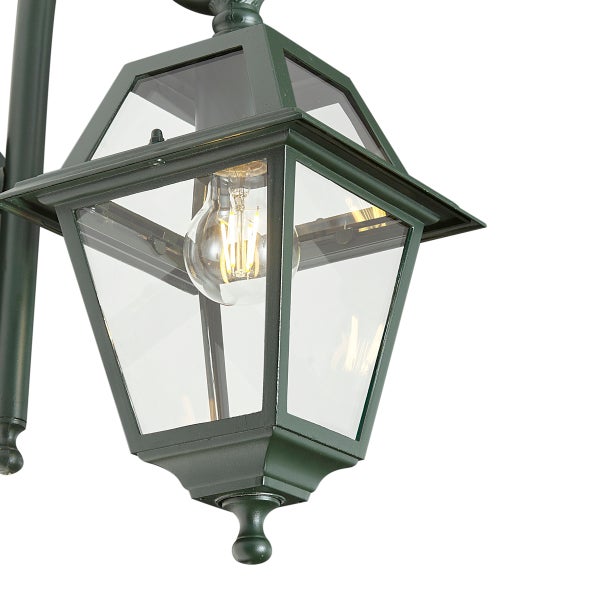 Klassische dunkelgrüne Außenwandleuchte aus Metall und Glas im Laternendesign mit sichtbarem Leuchtmittel.