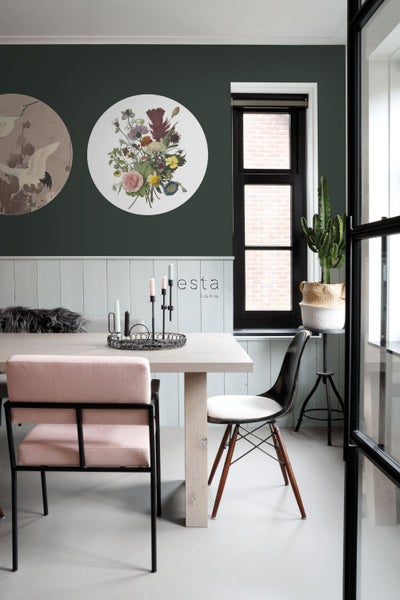Esszimmer mit Esstisch, Stühlen, Wanddekoration und Zimmerpflanze für eine helle und organisierte Atmosphäre.