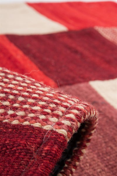 Gewebter Teppich mit Patchwork-Muster in Rot- und Beigetönen, Detailansicht der groben Struktur und Materialstärke.