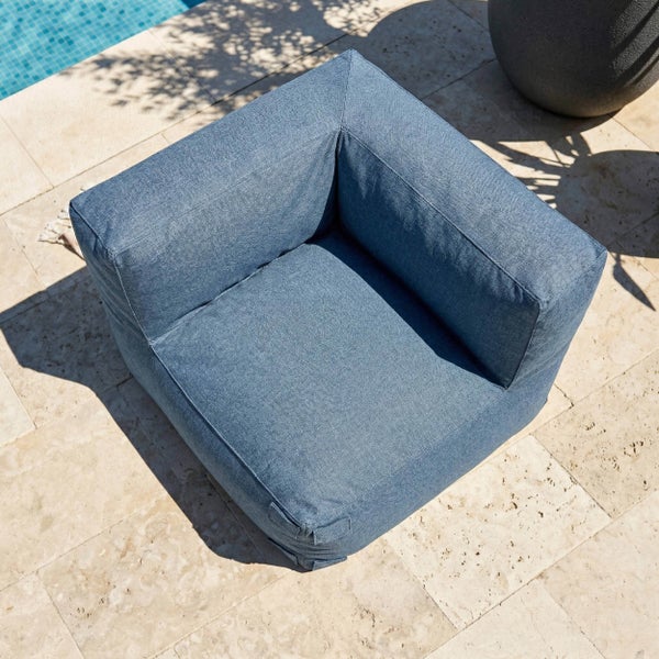Blauer Outdoor Sesselsitz aus Stoff auf einer Steinterrasse am Pool.