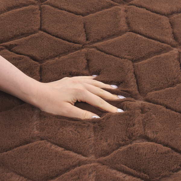 Hand auf braunem Plüschteppich mit Rautenmuster aus Kunstfaser.
