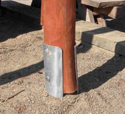 Pfostenträger aus Metall montiert an einem runden Holzpfosten.