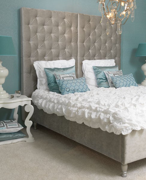 Schlafzimmer mit Bett, Nachttisch und Kronleuchter für eine helle und organisierte Atmosphäre.