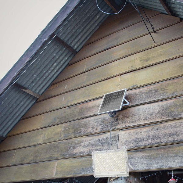 Solarpanel mit LED-Flutlichtstrahler an einer Holzwand montiert.