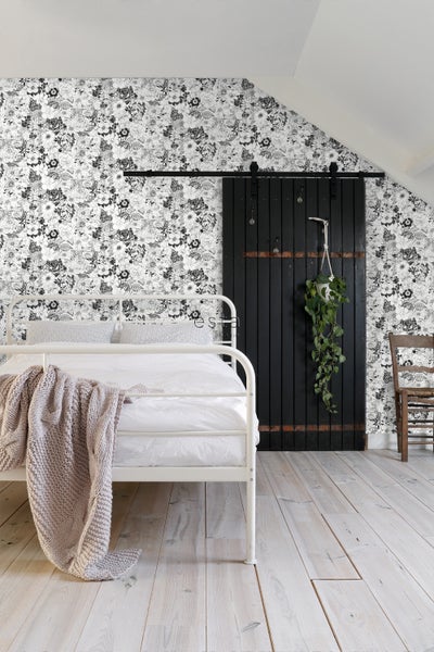 Helles Schlafzimmer mit floraler Tapete, Bett und Schiebetür