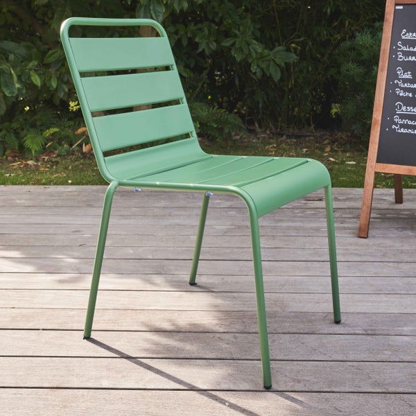 Moderner Gartenstuhl aus grünem Metall mit Lattenstruktur auf einer hellen Holzterrasse im Außenbereich.