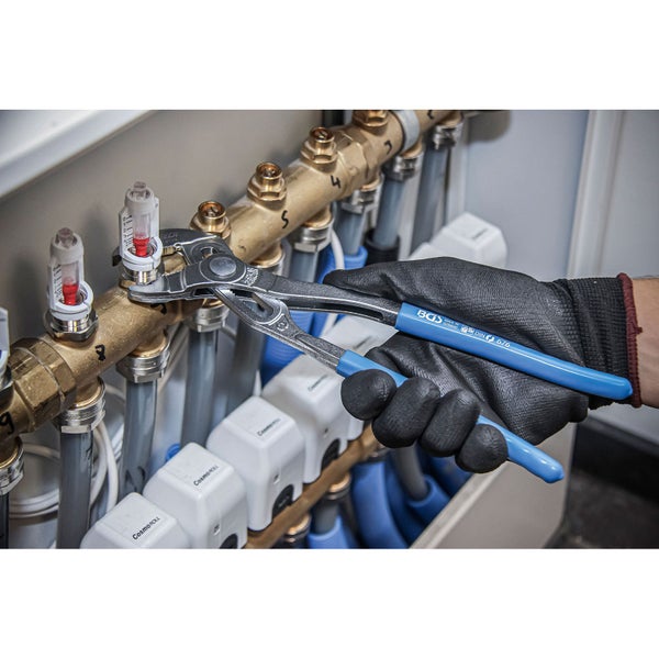 Eine Person mit Arbeitshandschuhen benutzt eine Rohrzange an einer Heizungsanlage.