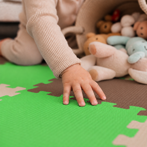 Kind spielt auf einer Puzzlematte aus Schaumstoff mit Spielzeugkorb und Plüschtieren im Kinderzimmer.