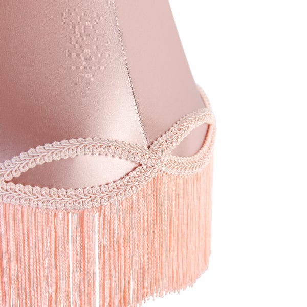 Detail eines Lampenschirms aus Stoff mit dekorativer Borte und Fransen.