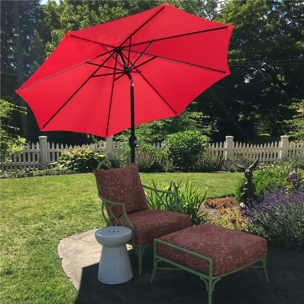 Szene im Garten mit einem roten Sonnenschirm, einem Stuhl, einer Fußstütze und einem Beistelltisch