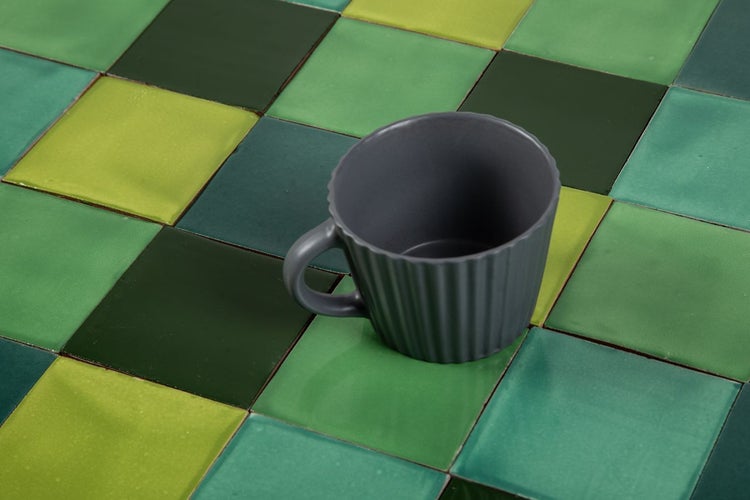 Quadratische Fliesen in Grün und eine Tasse