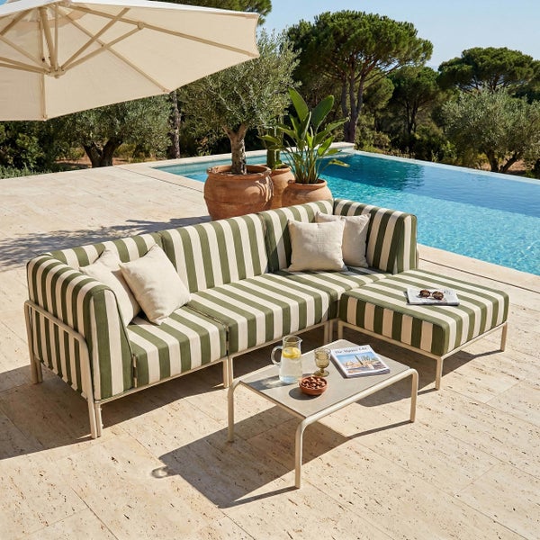 Modernes Outdoor Lounge-Set mit grün-weiß gestreiften Polstern auf einer hellen Steinterrasse am Pool, inklusive Ecksofa und Couchtisch.