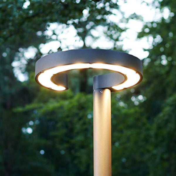 Moderne LED-Außenleuchte als Wegeleuchte mit ringförmigem Leuchtenkopf und warmweißem Licht in einer Gartenumgebung.