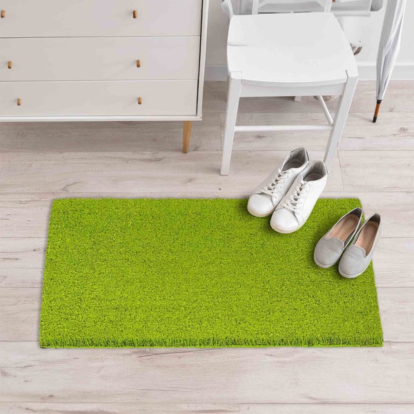 Grüne Fußmatte im Eingangsbereich mit Kommode und Stuhl
