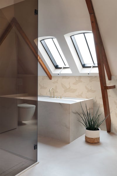 Ein Badezimmer im Dachgeschoss mit Badewanne, Dachfenstern und Dusche.