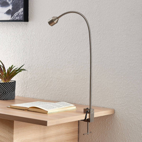 LED-Klemmleuchte aus Metall mit flexiblem Hals an einem Holzschreibtisch neben Buch und Pflanze, helles und organisiertes Arbeitszimmer.