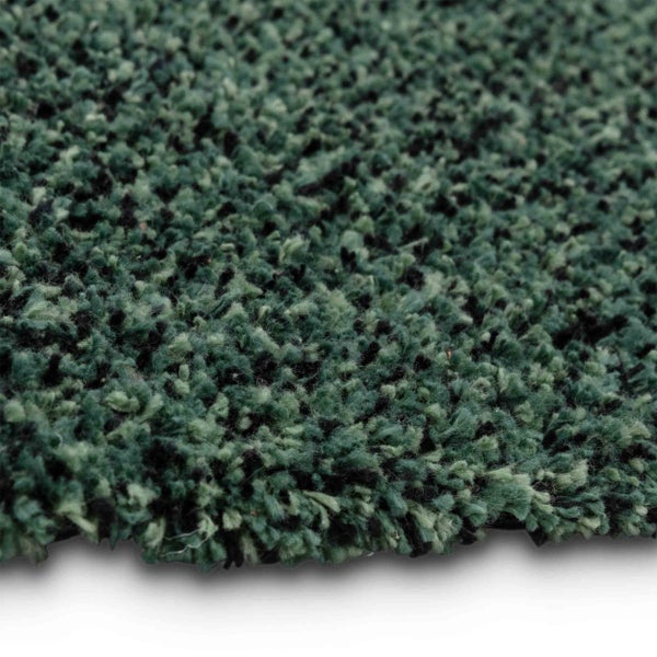 Nahaufnahme eines Hochflor-Teppichs mit strukturierten grünen und schwarzen Fasern in Shaggy-Optik.