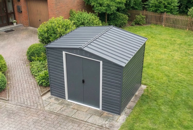 Metallgerätehaus mit Satteldach und Doppeltür, auf Steinplatten in einem Garten neben einer Rasenfläche.