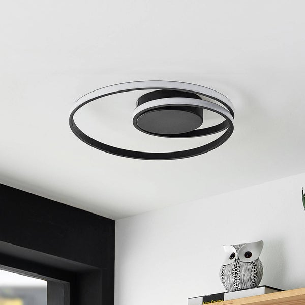 Moderne LED-Deckenleuchte mit zwei überlappenden kreisförmigen Ringen in Schwarz und Weiß, montiert in einem hellen, modern eingerichteten Raum.