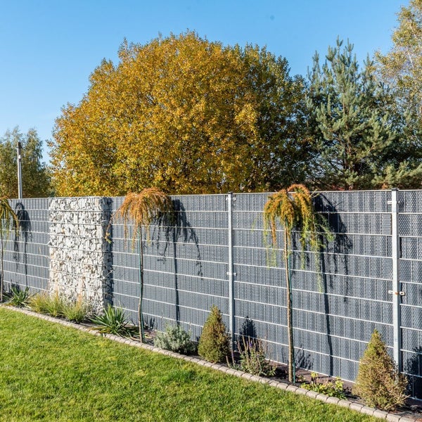 Gabionenzaun mit Steinen und Bewuchs im Garten