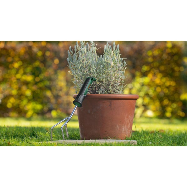 Gartenharke mit Pflanze im Topf