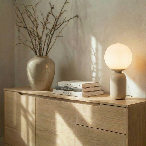Dekoratives Interieur mit Kommode, Lampe, Vase und Büchern