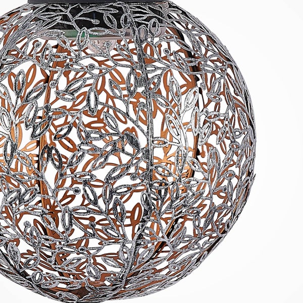 Nahaufnahme einer kugelförmigen Solarleuchte für den Garten mit einem dekorativen Blattmuster aus Metall.