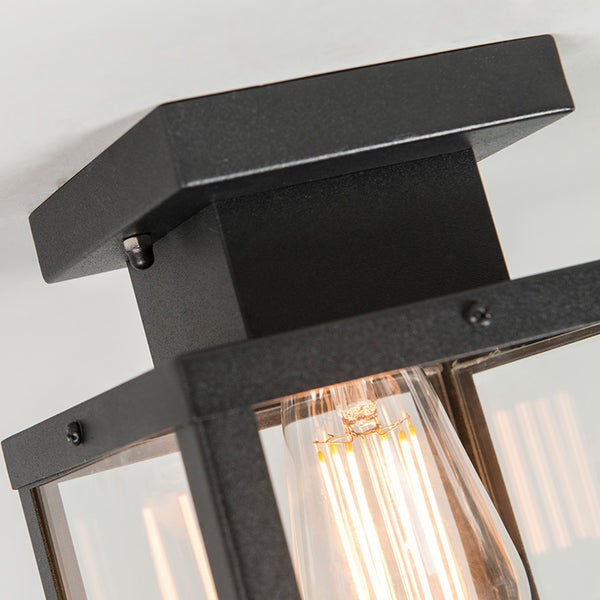 Schwarze Deckenleuchte im Laternen-Stil mit klarem Glas und leuchtendem LED-Filament-Leuchtmittel.