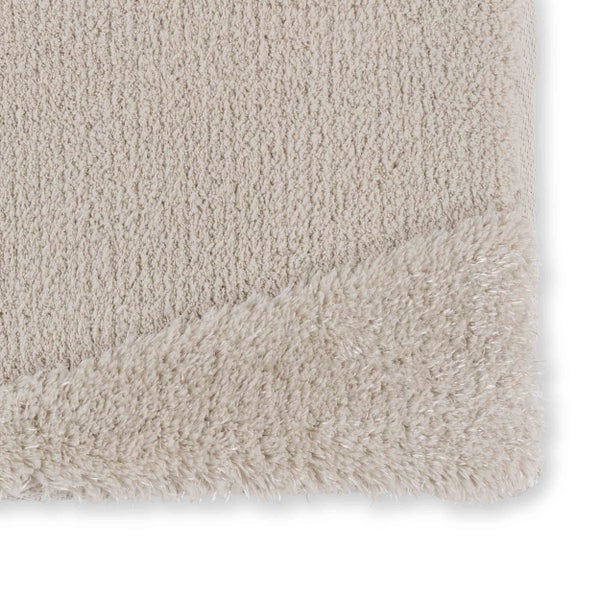 Nahaufnahme einer Badematte mit weichem, dichtem Flor und einer umgeklappten Ecke, die die Textur auf beiden Seiten zeigt.