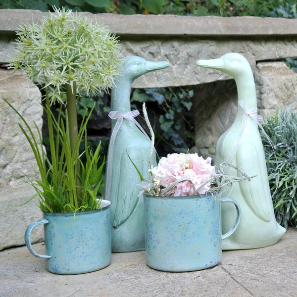 Dekorative Szene mit Entenfiguren und Blumenarrangements in Tassen