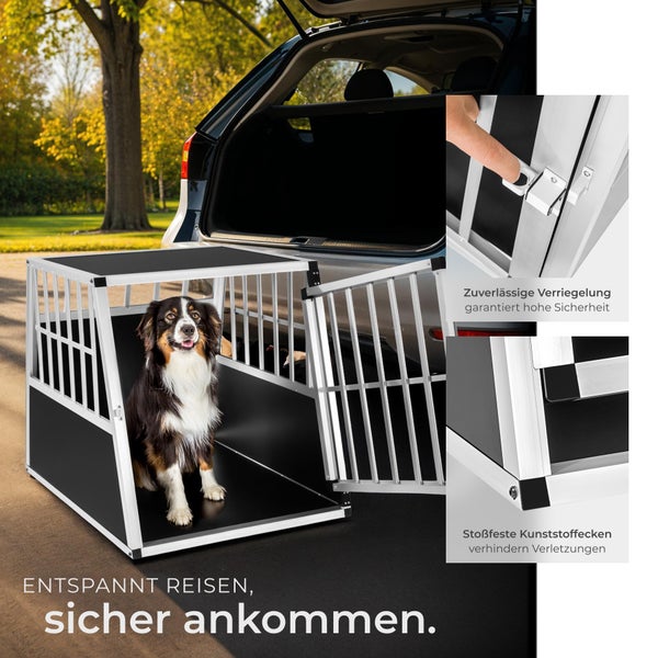 Hund in einer Hundebox aus Aluminium im Kofferraum eines Autos
