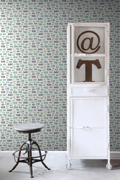 Szene mit einem weißen Rollcontainer, einem Barhocker im Industriestil und einer gemusterten Tapete